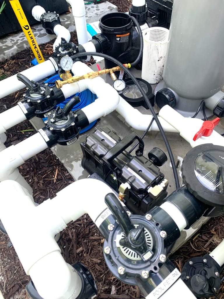 Pressure-testing rig connected to pool plumbing lines at the equipment pad